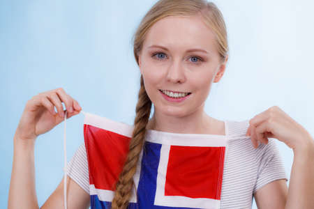 Blonde girl braid hair with norwegian flag, on blue. Scandinavian people.の写真素材