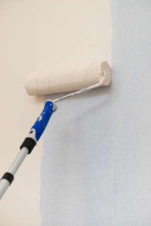 Person appplying paint on wall using roller brush. Home renovation concept.の写真素材