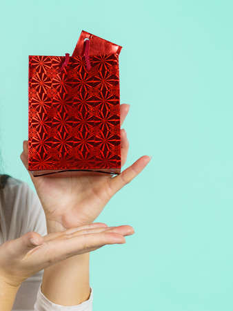 Female holding present red gift bag in hand, on blue