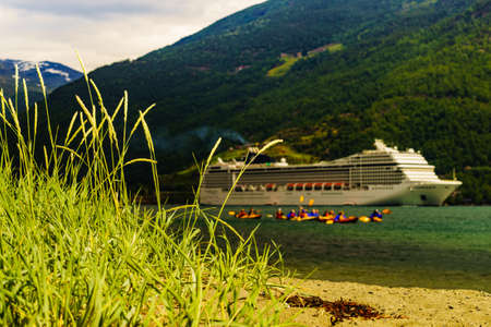 Travel, voyage and activity concept. People kayaking and cruise ship on fjord Aurlandsfjord in...