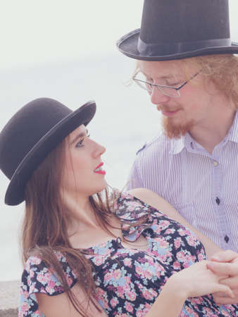 Vintage retro couple, man and woman enjoying their romantic date outside wearing fedora hats by seasideの写真素材