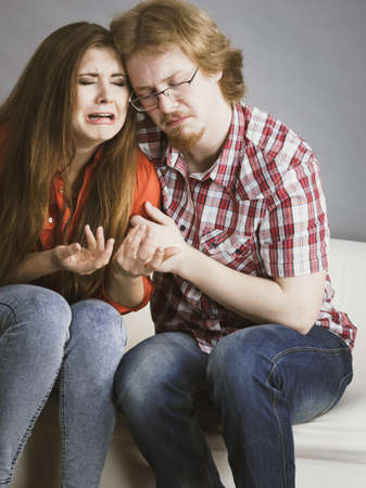 Man comforting woman sitting on sofa. Friend confiding to friend having a serious talk. Couple...
