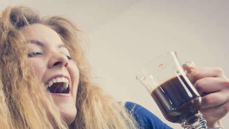 Positive woman holding black coffee about to drink. Getting morning energy, hurry up before going to work.の写真素材