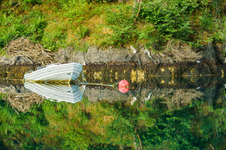 Little moored boat on water surface, fjord landscape, Norway Europeの写真素材