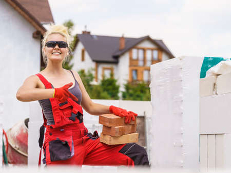 Strong pretty woman working on construction site, building house, installing bricks. Industrial work concept.の写真素材