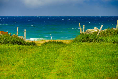Nature summer landscape. Countryside view field with old rustic fence on norwegian south seacoast.の写真素材