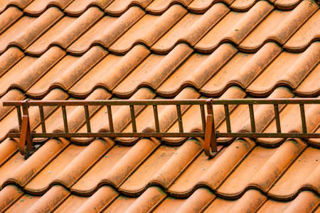 Red tiles roof with snow guards, safety barrier. House detailの写真素材