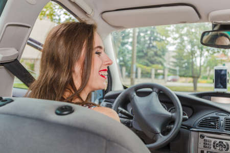 Young woman behind steering wheel. Female passing driver license exam, driving a car.