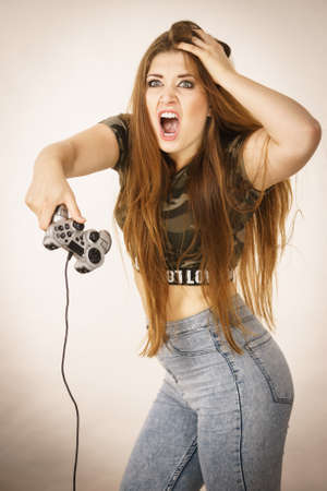 Young angry mad woman playing on the video console holding game pad. Gaming gamers concept.
