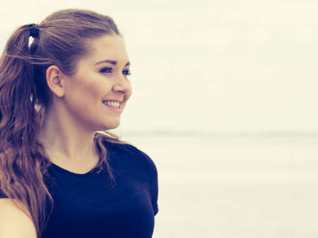Happy teen woman enjoying her leisure time. Female having long brown hair posing with sky in...