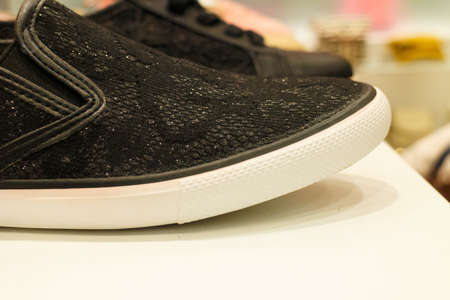Black male female unisex trainer sneakers shoes on shop shelf in mall