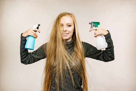 Girl messy long dry hair holding bottle, applying thermal protect hair spray.の写真素材