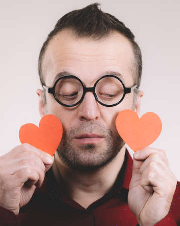 Adult serious man holding two red hearts. Romance love valentines day concept.の写真素材