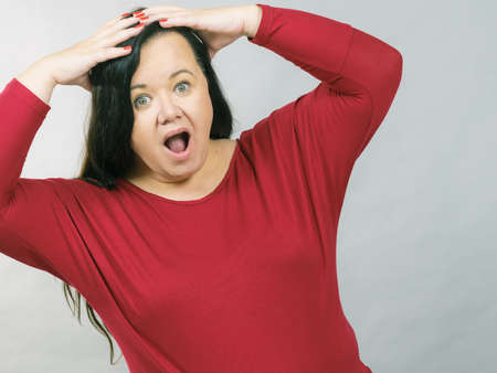 Plus size adult woman looking shocked surprised stunned, grabs her head. Human emotion face...