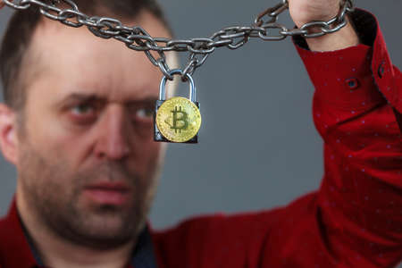 Man having problems with crypto currency. Adult guy being tied up with block chain bitcoin.