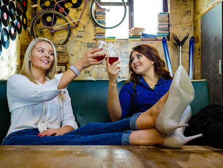 Girls best friends drinking alcohol in night club, gossiping and talking