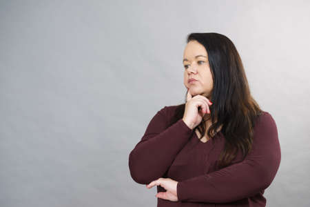 Thinking adult woman, plus size female gesturing with hands seeking for solution, having...