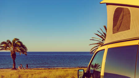 Camper van with tent on roof camping on mediterranean coast with palm trees in Spain. Percheles Beach. Holidays and travel in motor home.の写真素材