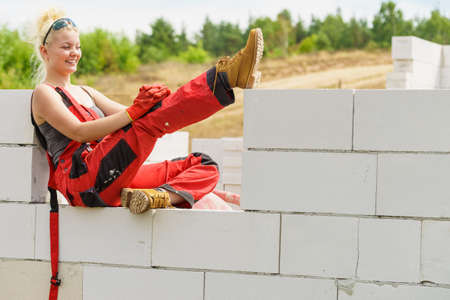 Woman in dungarees relaxing after hard work on construction site. Young female lying outdoor taking a breakの写真素材