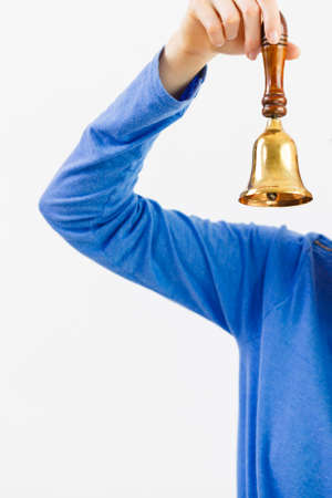 Woman hand wearing blue long sleeve shirt holding old fashioned golden bell.の写真素材