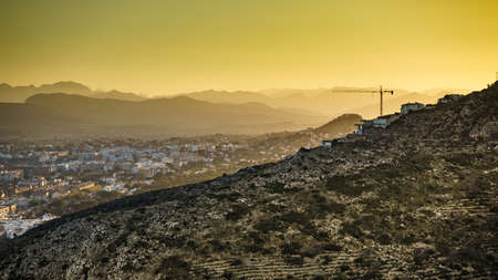 Building activity. Construction site with crane industrial equipment, spanish coast landscape