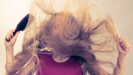 Haircut coiffure haircare concept. Crazy girl with blowing long blonde hair holding brush comb.