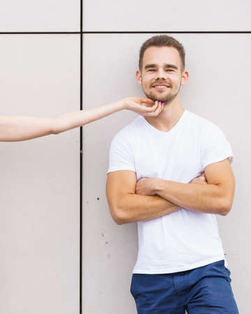 Date and love concept. Blonde young woman touching tender her boyfriend outdoors.の写真素材