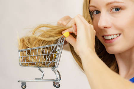 Girl with her long blonde hair in shopping cart. Haircut haircare and shopping conceptの写真素材