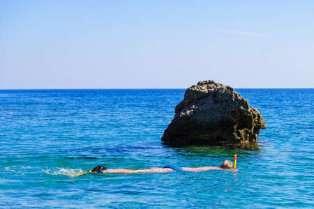 Man diver with snorkel equipment snorkeling mask tube in ocean water. Summer vacation swimming fun concept.の写真素材