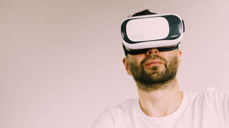 Adult short bearded guy exploring virtual reality wearing VR goggles being into technology.