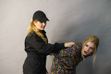 Shoplifting is a crime. Young fashionable woman being caught on stealing clothes by female security...