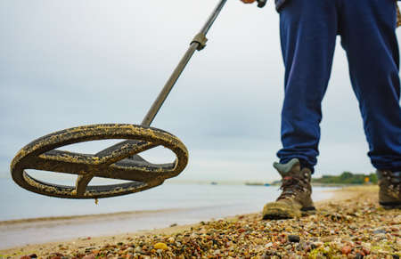 Man using electronic metal detector devic on sea sand beach. Detecting hobby.の写真素材