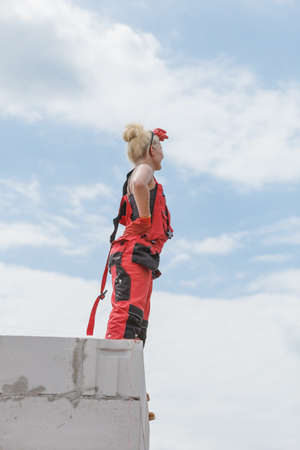 Blonde woman wearing dungarees relaxing after hard work on construction site. Female taking break dreaming of building her home.の写真素材