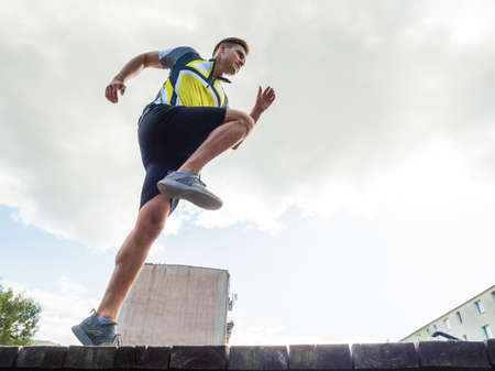 Young handsome guy in sportswear suit running outdoors in park. Botton view