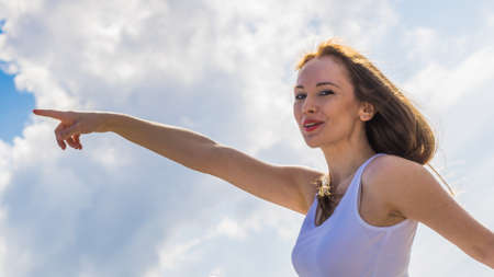 Girl outdoor against blue sky pointing with finger