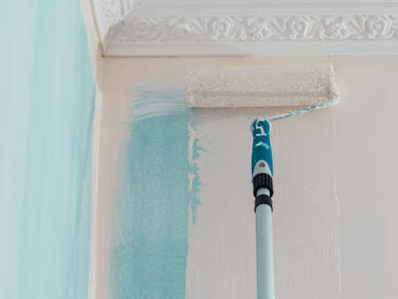 Person appplying paint on wall using roller brush. Home renovation concept.の写真素材