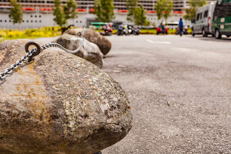 Parking area with stone chain fence and cruise ship on fjord in distance, norwegian tourist...