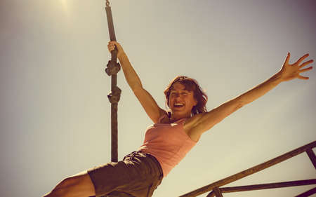 Adult freedom woman having fun on zipline, descend on rope, cable aerial ropeslide. Happiness and...