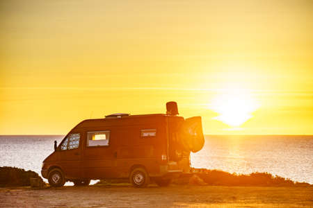 Camper van recreational vehicle at sunrise on mediterranean coast in Spain. Camping on nature beach....