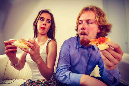 Man and woman spending time together. Couple or friends eating delicious cheesy pizza.の写真素材