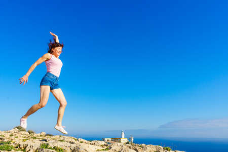 Woman enjoying trip with rv motor home, jumping in the air at camper. Mesa Roldan lighthouse...
