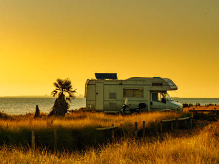 Camper recreational vehicle at sunrise on mediterranean coast in Spain. Camping on nature beach....
