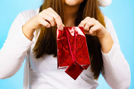 Female holding present red gift bag in hands, on blue