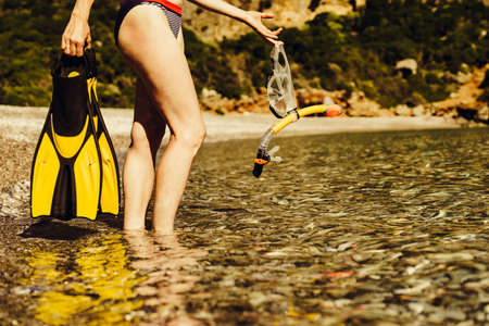 Unrecognizable mature female with snorkel equipment flippers and snorkeling mask tube on beach sea...