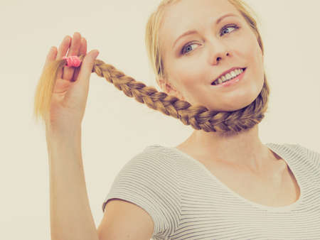Blonde girl with long braid hair. Haircare, hairstyling.の写真素材