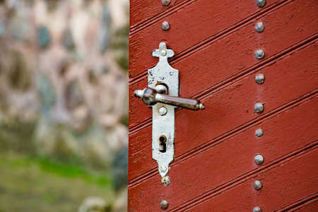 Old wooden red brown color vintage door with metal rivets. Close up architectural detailの写真素材