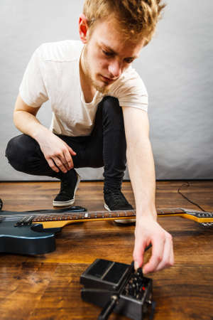 Man with musical instrument setting up guitar audio stomp box effects and cables in music studioの写真素材