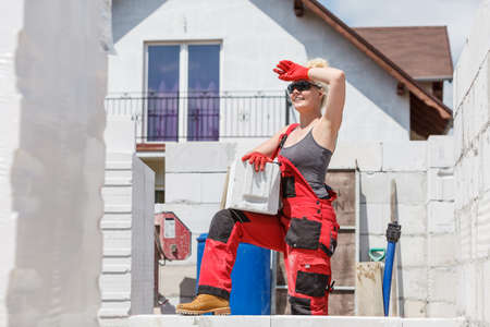 Strong pretty woman working on construction site, building house, installing gray airbricks. Industrial work concept.の写真素材