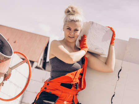 Strong pretty woman working on construction site, building house, installing gray airbricks. Industrial work concept.の写真素材