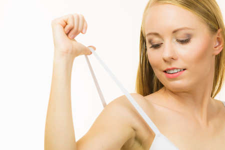 Young woman holding bra strap. Straps keep falling down problem. Female breast in lingerie. Bosom and underwear concept.の写真素材